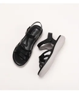 Detail of black wedge sandals with crossover straps and thick gray anti-slip wave sole