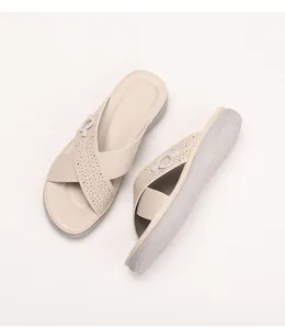 Detail view of beige wedge slide sandals featuring laser-cut straps and round buckles