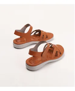 Detail view of brown wedge sandals with crisscross leather straps and adjustable velcro strap