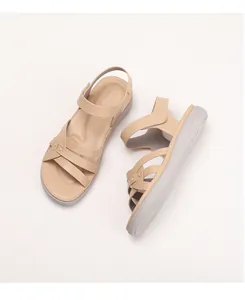 Close-up of beige wedge sandals featuring criss-cross straps and Velcro ankle closure