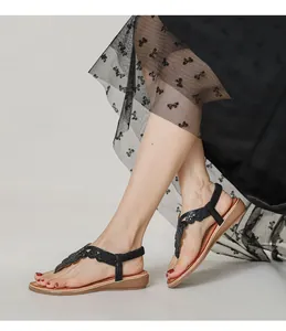 Détail de sandales compensées bohèmes avec motifs floraux en paillettes sur bride noire
