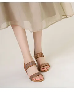 Detail of bohemian wedge sandals featuring brown rhinestone straps on female feet