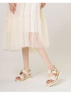 Detail von beigen Plateau-Sandalen mit großen Goldschnallen und Riemchen am Modell