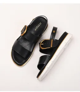 Details von schwarzen Ledersandalen mit großen Goldschnallen und weißer Plateausohle