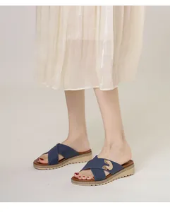 Detail of bohemian navy blue leather cross-strap sandals with gold buckle and platform sole