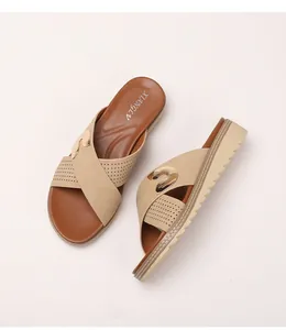 Detail of bohemian wedge flip flops featuring beige cutout straps and gold metal buckles
