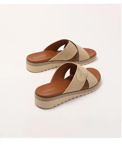 Detail of bohemian wedge sandals with beige laser-cut straps and gold metal buckle