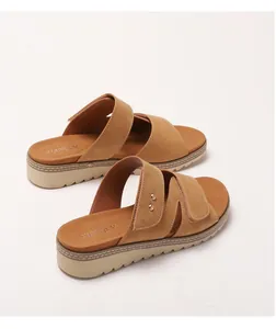 Détail de sandales compensées marron avec brides croisées et rivets dorés sur le côté