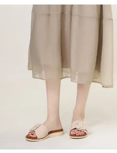 Detalle de sandalia de cuña beige elegante con una gran hebilla decorativa cuadrada