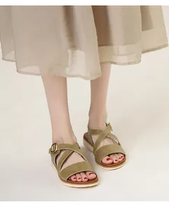 Detail of olive green wedge sandals with crisscross straps and gold buckle on a model