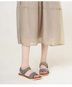 Detail of grey wedge sandals featuring black and white striped woven elastic straps