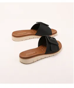 Detalle de sandalias de cuña con correa de cuero sintético negro y hebilla cuadrada