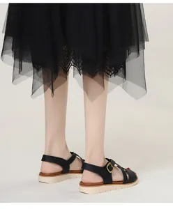 Detail of black leather straps with gold buckle on thick-soled wedge sandals for women