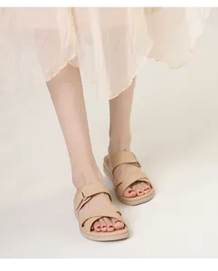 Detail view of khaki cross-strap wedge sandals with adjustable ankle buckle on model