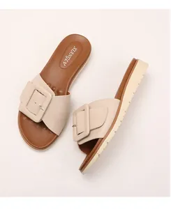 Detalle de sandalias de cuña beige con hebilla decorativa grande y suela de plataforma