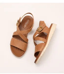 Close-up of brown cross-strap platform sandals with textured leather and gold buckle
