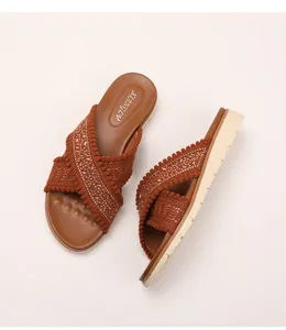 Detail van geweven kruisbanden met strass en kralen op de bohemien wigvormige slippers