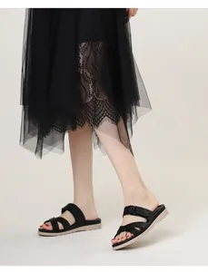 Close-up of black multi-strap wedge sandals styled with a lace skirt on a model