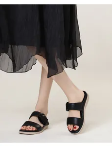 Detail von schwarzen Kunstleder-Sandalen mit runder Schnalle und rutschfester Sohle