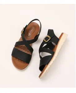 Detail of wedge sandals featuring black crisscross straps and gold adjustable buckles