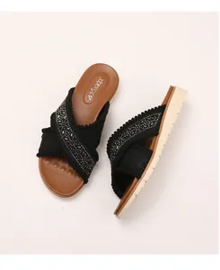 Detail van boheemse sleehak slippers met strass kruisbanden en getextureerde rubberen zool