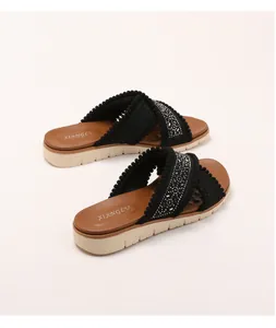 Detail van boheemse slippers met sleehak, geborduurde kruisbanden en fonkelende kristallen