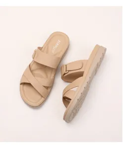 Close-up of beige platform wedge sandals with crisscross straps and textured footbed