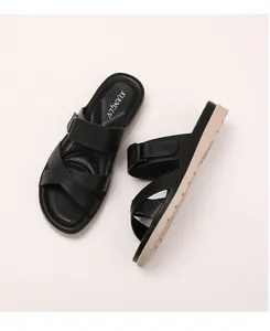 Close-up of black leather platform sandals featuring cross straps and adjustable velcro strap
