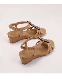 Dettaglio di sandalo con zeppa boho con perline, catene dorate e cinturino elastico