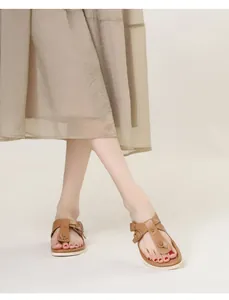 Gros plan de sandales plates marron à bride en T avec boucle et semelle blanche