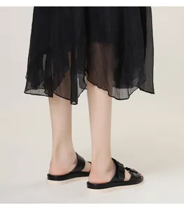 Close-up of black leather double-strap slides with metal buckles and thick white platform