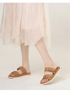 Close-up of tan dual-strap sandals featuring matching buckles and a thick white sole