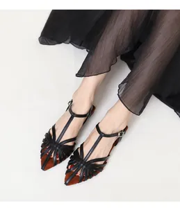 Macro detail of black T-strap cage sandals with textured sole and woven hollow design