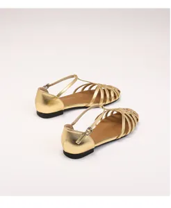 Detail of gold metallic cage sandals with T-strap buckle and non-slip sole