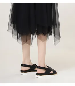 Close-up of black platform sandals with wavy white soles and golden trim detailing