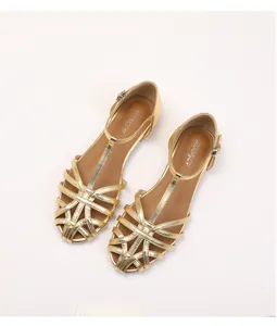 Close-up of golden woven sandals featuring a T-strap buckle and metallic finish details