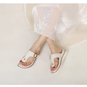 Detail view of cream T-strap flip flops with gold buckle and comfortable thick sole