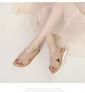 Detail of beige platform sandals with cross straps and elegant gold trim on the sole