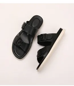 Close-up of black platform slides with dual adjustable buckles and thick cream sole