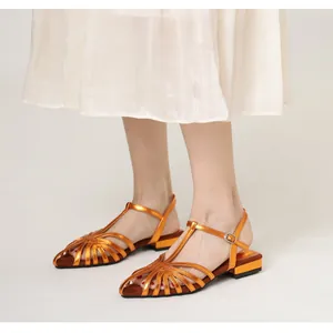 Detail of metallic orange woven leather cage on low block heel Roman sandals