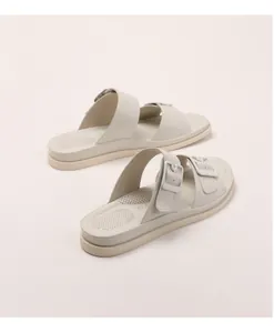 Detail of beige double-strap slides featuring adjustable square buckles and breathable footbed