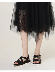 Detail of black wedge sandals with crossover straps and gold trim on the platform sole