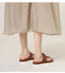 Detail view of brown leather platform sandals with gold buckles and white serrated soles