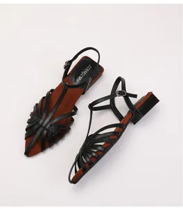 Detail view of woven strappy flat sandals with black T-bar straps and brown padded insoles