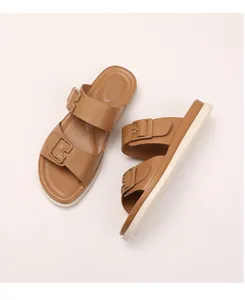 Detail of caramel double-strap slides featuring adjustable buckles and breathable footbed