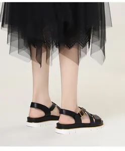Detail of black wedge sandals with golden buckle and thick white rubber sole on model