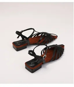 Detail of woven low-heel Roman sandals with adjustable buckle and soft black straps
