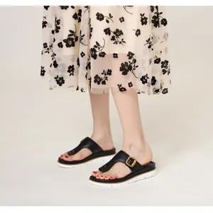 Detail of black flip-flop sandals with gold square buckle and white platform sole