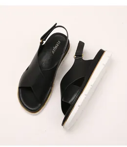 Close-up of black platform sandals with cross-straps and adjustable metallic heel buckle