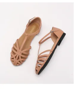 Close-up of woven cutout toe detail on beige minimalist flat sandals with buckle strap